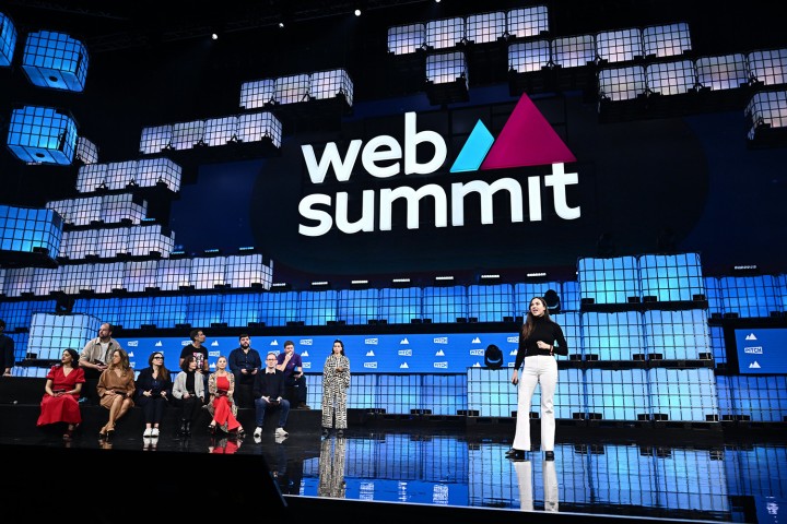 Eine Frau präsentiert auf dem Web Summit 2023 in Lissabon, während das Publikum aufmerksam zuhört und die Atmosphäre lebhaft ist.